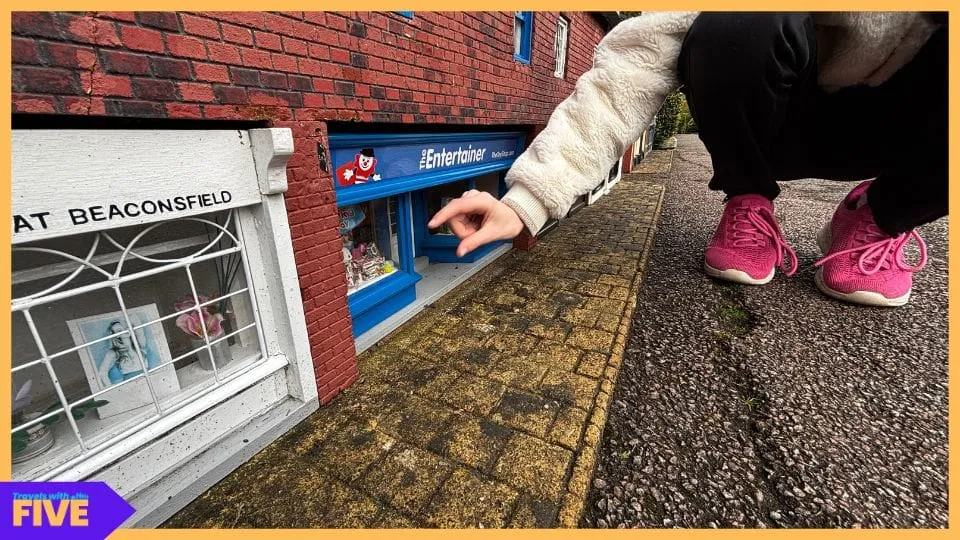 Pointing at a tiny shop window in Bekonscot model village