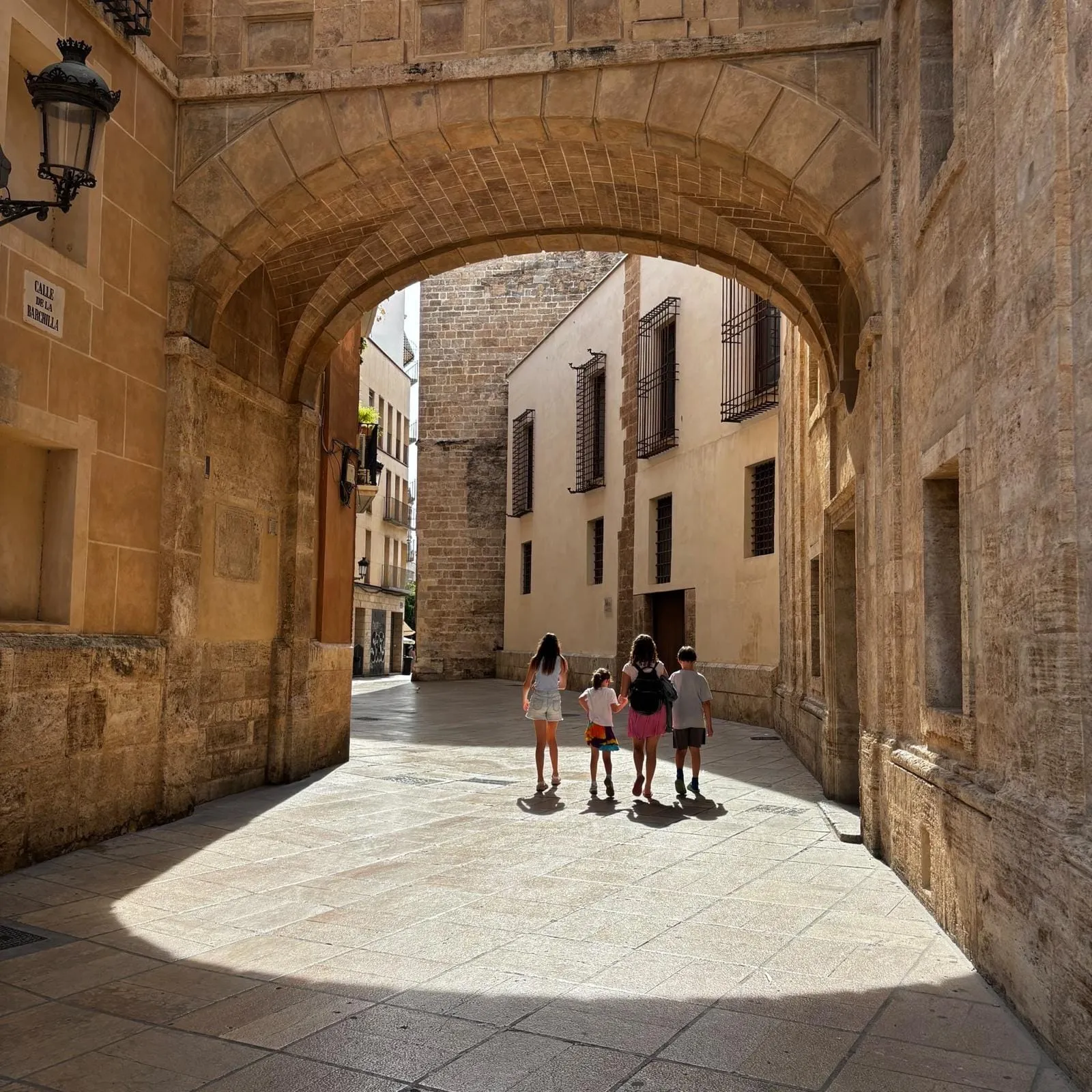 The kids walking through a stone archway in Valencia’s old town